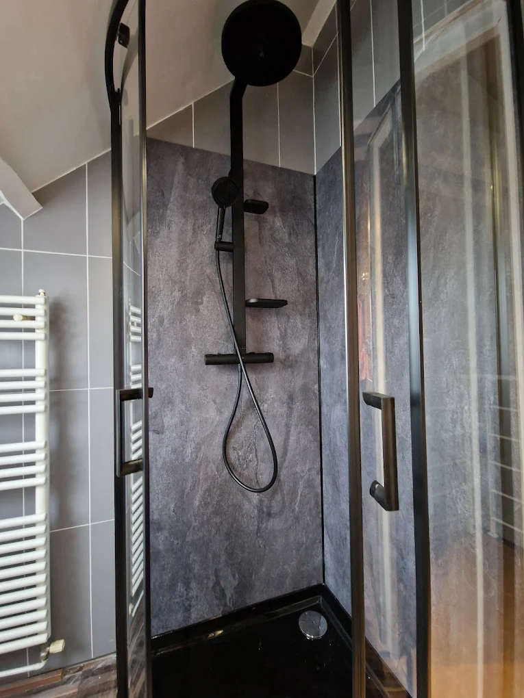 Rénovation d'une douche à Château-Thébaud — panneaux muraux effet pierre, receveur quart-de-rond et colonne de douche noire