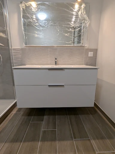 Rénovation salle de bain au Bignon — meuble vasque blanc, miroir, faïence murale et carrelage au sol effet bois