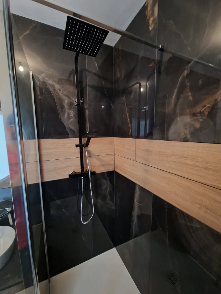 Rénovation salle de bain à Nantes — douche avec faïence grand format effet marbre noir, bandeau bois et colonne de douche noire